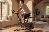 Zijaanzicht van de KingSmith WalkingPad Sprint Bike PB08S hometrainer vrijstaand in de woonkamer terwijl man aan het fietsen is
